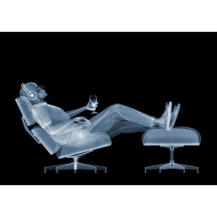 skeleton figure xray man laying back in chair with headphones and glass in hand with feet up on black background