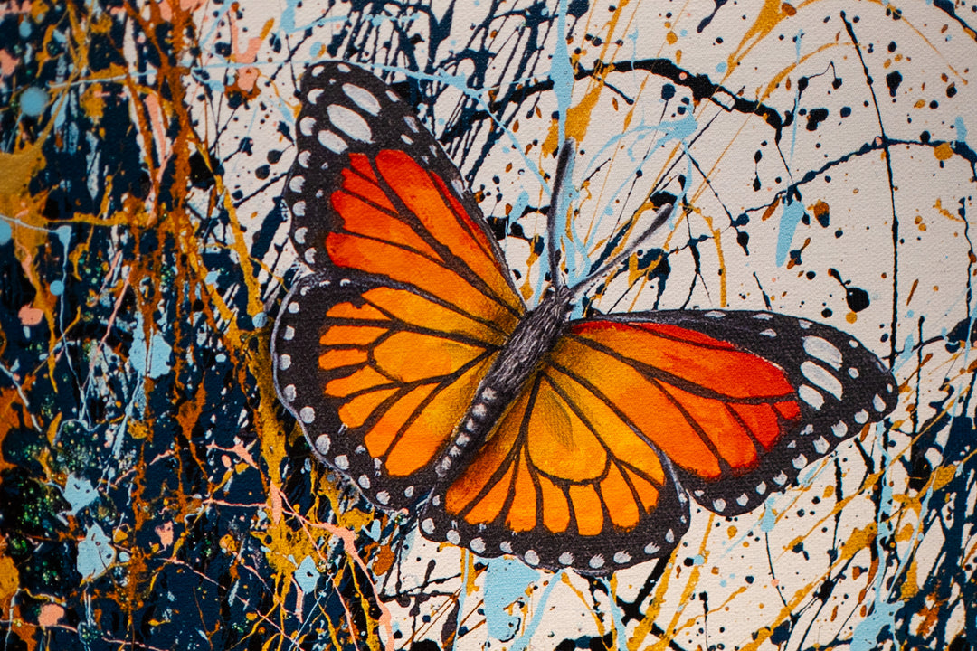 black and white woman flipping hair back with gold blue and black splatter paint, orange monarch butterflies in hair on white background