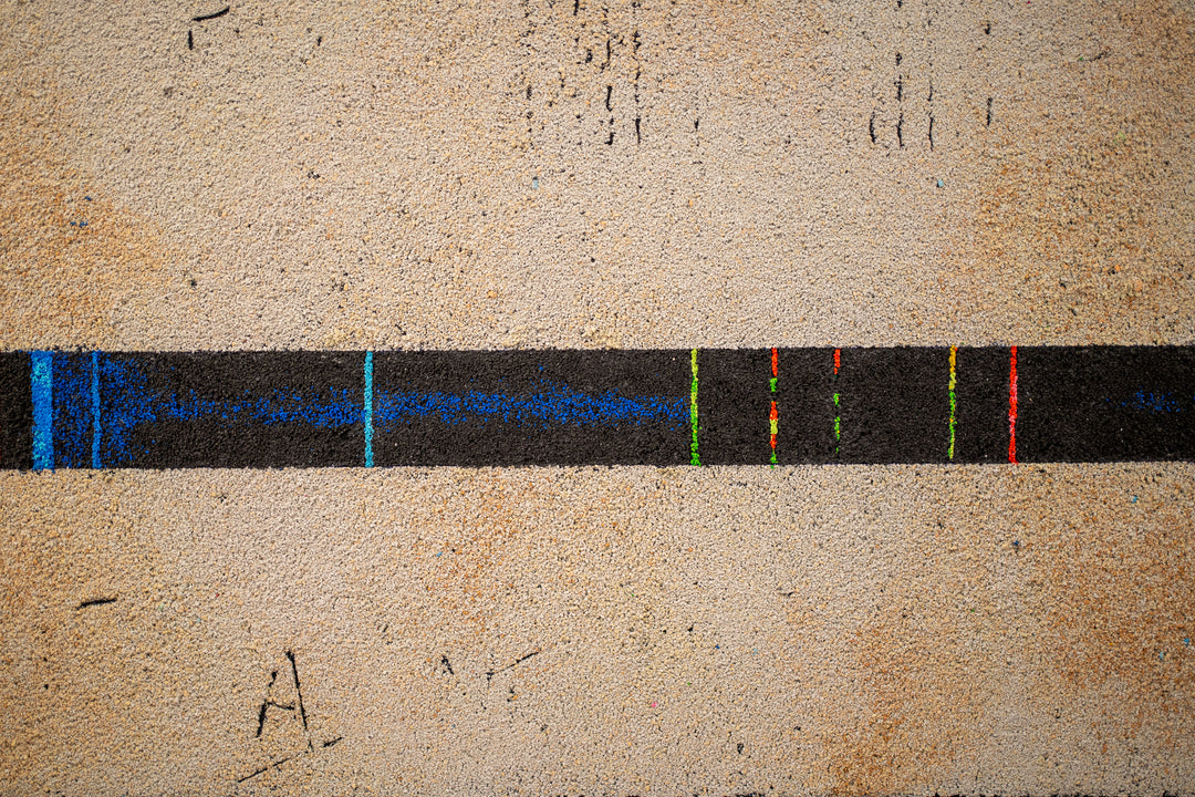 pigmented volcanic rock on canvas in beige tone with dots of color blue red purple green and static line across bottom abstract minimal textured painting