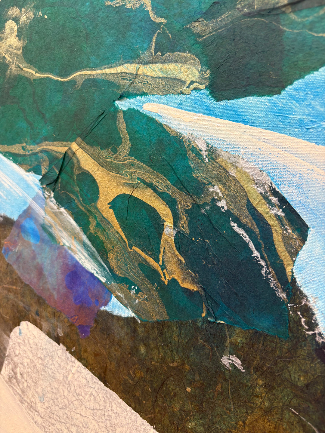 Close-up detail of Current Cameo showing layered collage materials: deep emerald green paper with gold leaf veining, diagonal white and blue brushstrokes, and dark marbled paper textures.