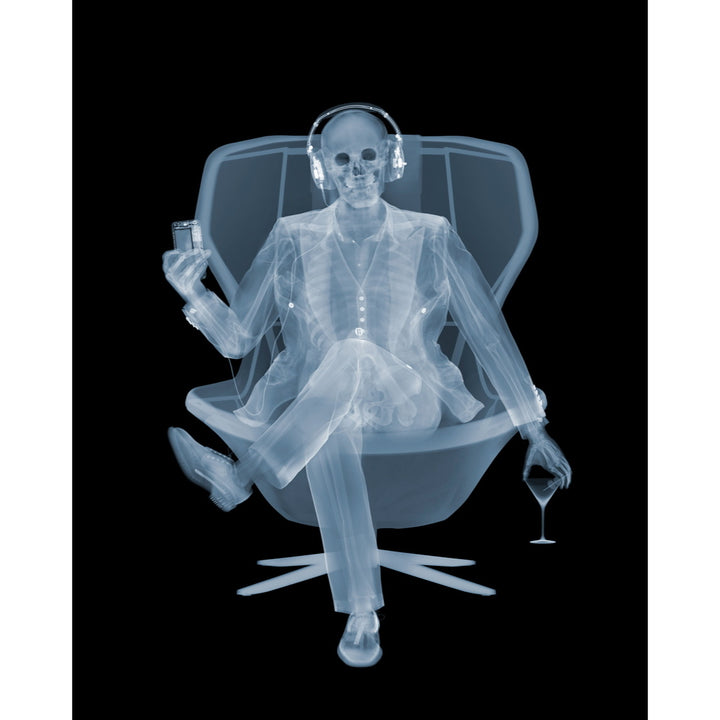 Framed Chromaluxe x-ray photograph by Nick Veasey of a skeleton listening to music with headphones in a swivel chair with a martini