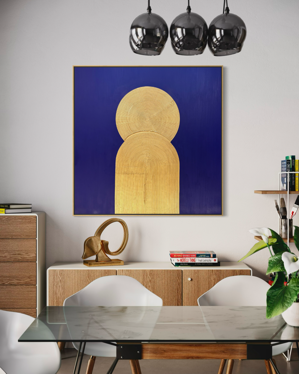 Lee in Cerulean, Halo Vaste I, joint compound and acrylic paint on canvas, 48 x 48 inches. Square deep blue painting with a gold circle and arch, hung in a dining room above a light wood sideboard, with a glass table, white chairs, and three dark glass pendant lights.