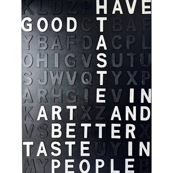 Steffanie Gerkin’s Have Good Taste Black 3D is a contemporary mixed-media typography artwork made with raised wood and acrylic letters on canvas, featuring a black monochrome alphabet grid with contrasting white letters that spell phrases including “Have Good Taste,” “Art,” “Better Taste,” and “People.”