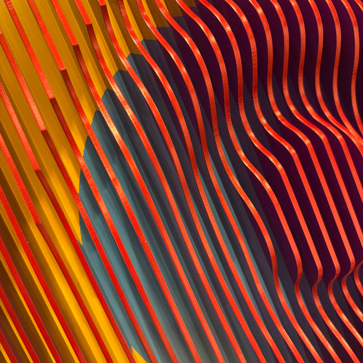 vertical stripes plexiglass abstract geometric with yellow and orange in back and pulsing round circular middle in blue when viewed at angle mostly red