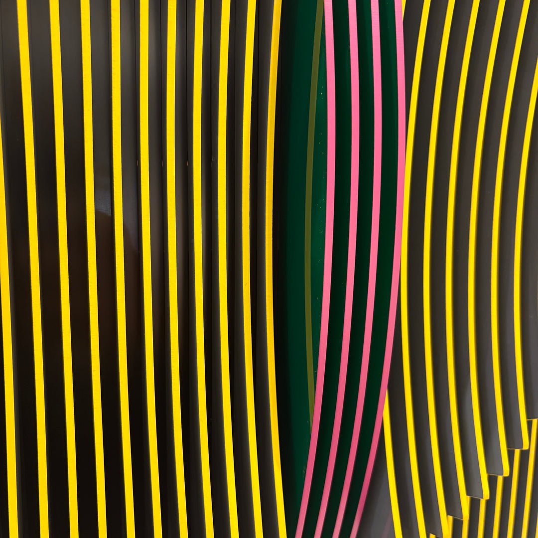 vertical stripes in black and yellow with circle in center offset optical illusion stripes with pink purple stripe down the middle