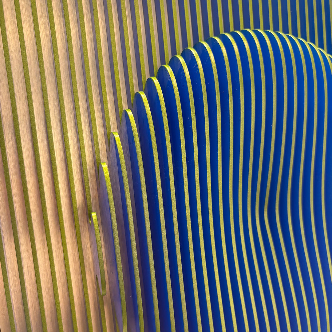 vertical green stripes with 3 dimensional circular shape emerging from center, when viewed from side ridges are blue optical illusion geometric abstraction sculpture
