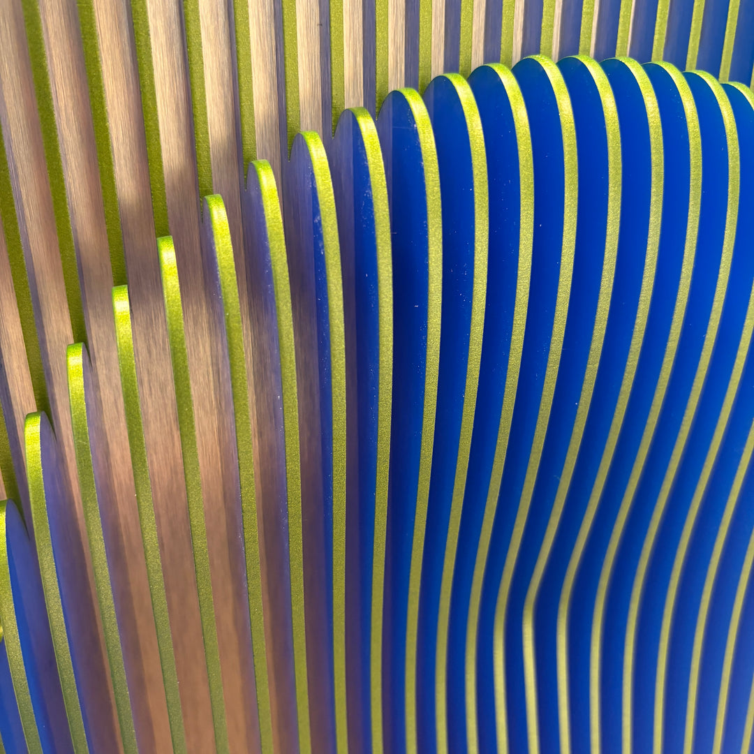 vertical green stripes with 3 dimensional circular shape emerging from center, when viewed from side ridges are blue optical illusion geometric abstraction sculpture