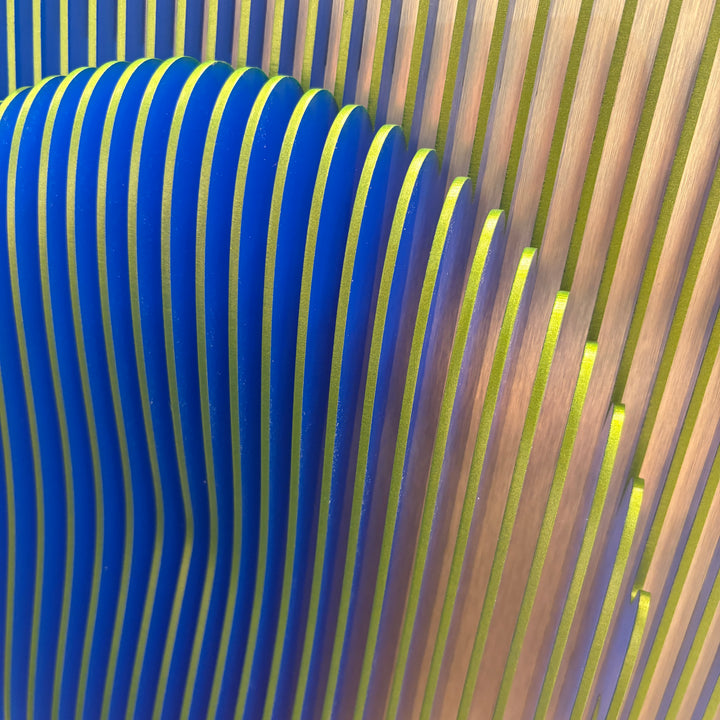 vertical green stripes with 3 dimensional circular shape emerging from center, when viewed from side ridges are blue optical illusion geometric abstraction sculpture