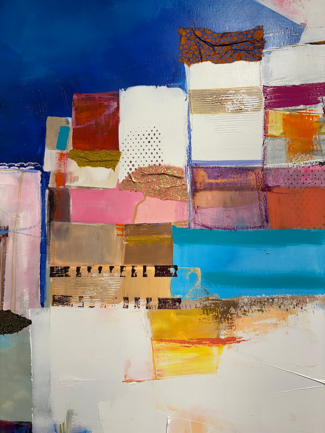 collage of paint fabric foil shapes built up in mountainous form in white pinks and orange on bright blue cloudy background abstract collage patterns 
