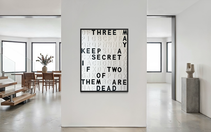 Contemporary 3D text artwork by Chicago artist Steffanie Gerkin titled Keep A Secret 3D, featuring raised black and white wood letters arranged in a structured alphabet grid on a white canvas. The typographic composition spells “Keep a Secret,” “Three May,” and “Two of Them Are Dead,” creating a bold monochrome mixed-media wall art piece with graphic, conceptual, and pop art qualities.