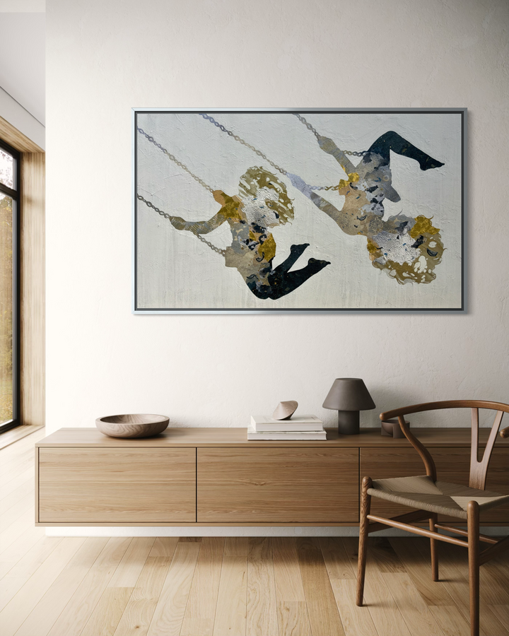 Swinging Silhouettes II by Christopher Peter displayed in a modern Scandinavian-style interior, framed in silver and hung on a white wall above a light wood sideboard, with a Wishbone chair and table lamp.
