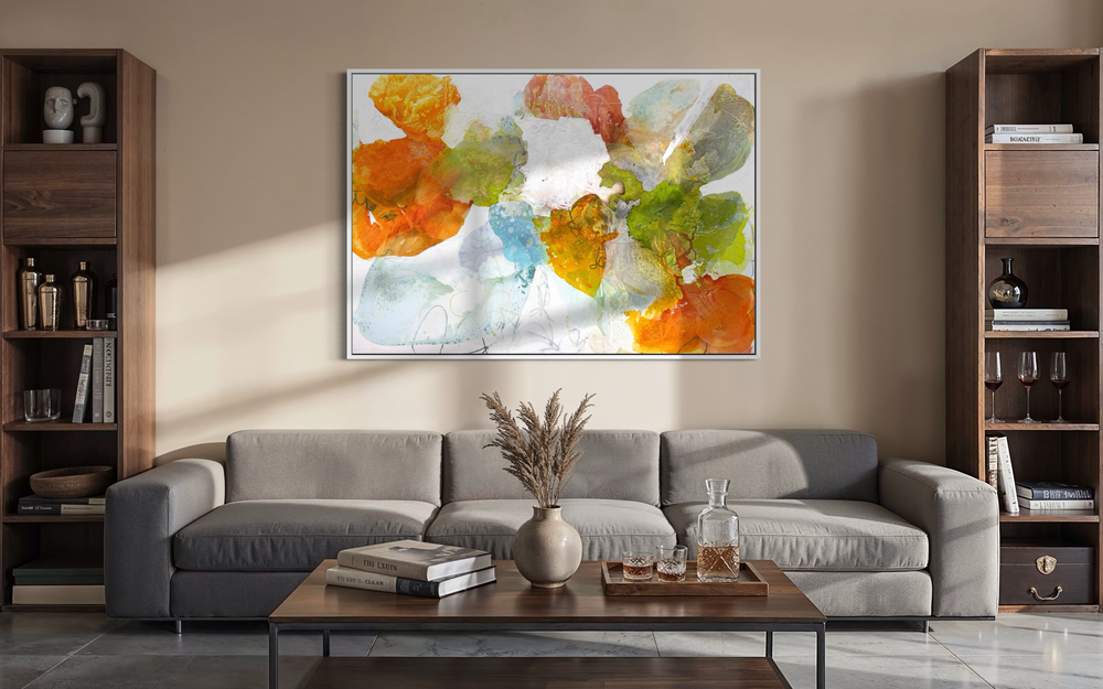 Liz Barber, Spring Promise, acrylic paint, ink, watercolor, graphite, and pastel on canvas, 72 x 50 inches. Horizontal abstract composition of overlapping rounded shapes in orange, coral, lime green, olive, sky blue, pale aqua, and white with fine graphite lines on a white background, shown in a white frame above a gray sofa between wood bookshelves in a living room.