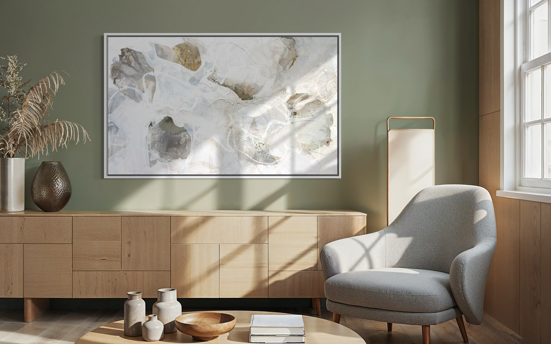 Framed "Summer Light 3" painting by Liz Barber displayed on a sage green wall above a wooden credenza, beside a gray armchair