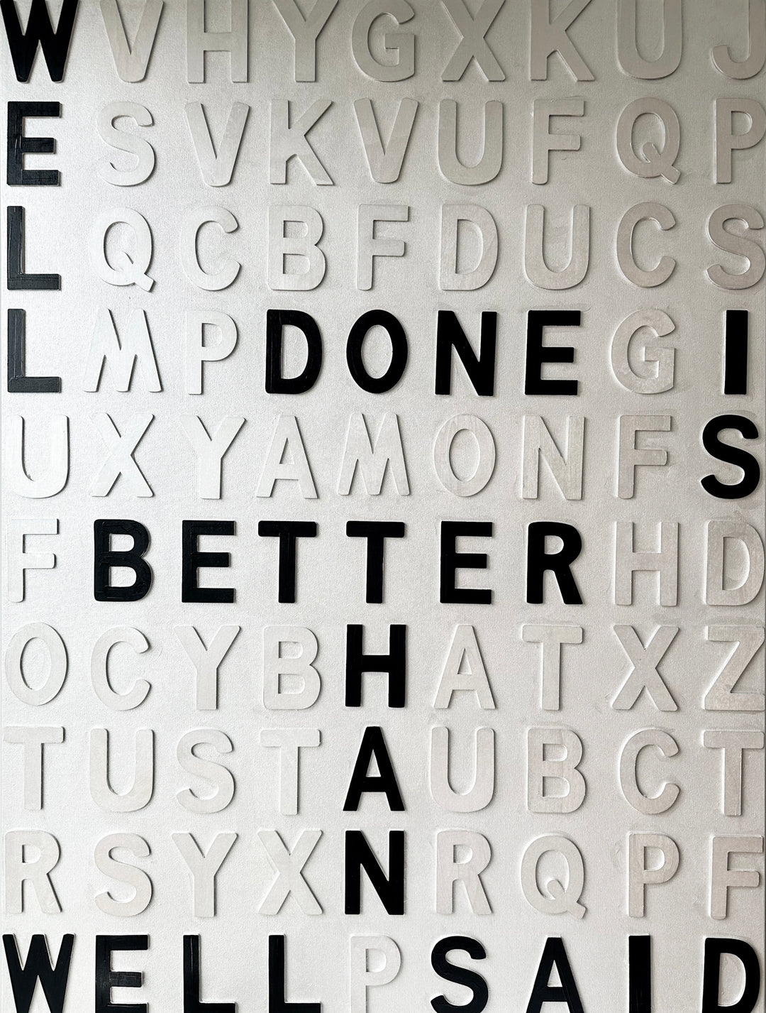 Contemporary 3D text artwork by Chicago artist Steffanie Gerkin titled Well Done 3D, featuring raised black and white wood letters arranged in a structured alphabet grid on a white canvas. The monochrome typographic composition spells the phrase “Well Done Is Better Than Well Said,” creating a bold conceptual wall art piece with graphic text-based design, pop art influence, and contemporary mixed-media style.